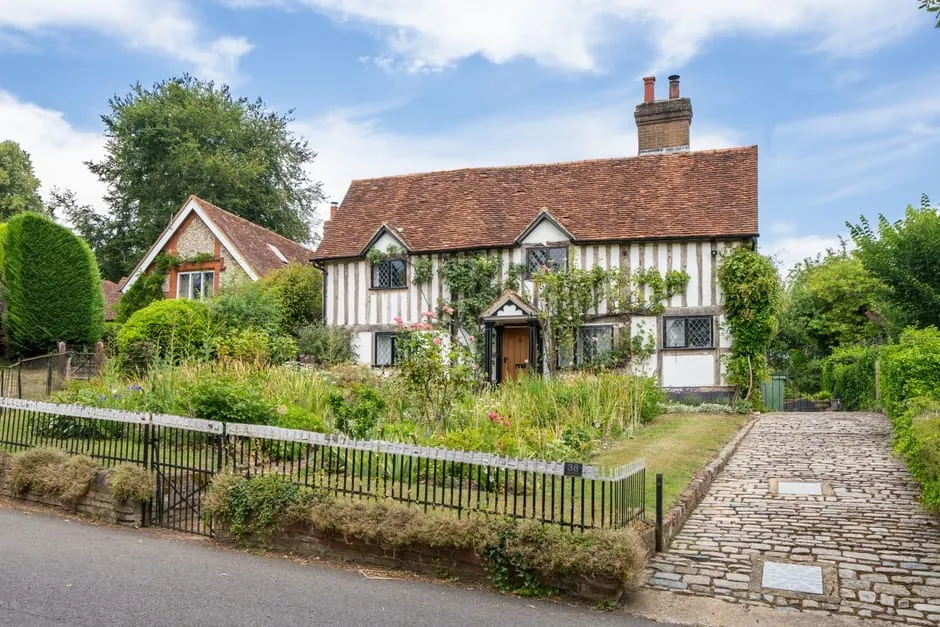 A timber-framed rural English cottage with a tiled roof and cottage garden