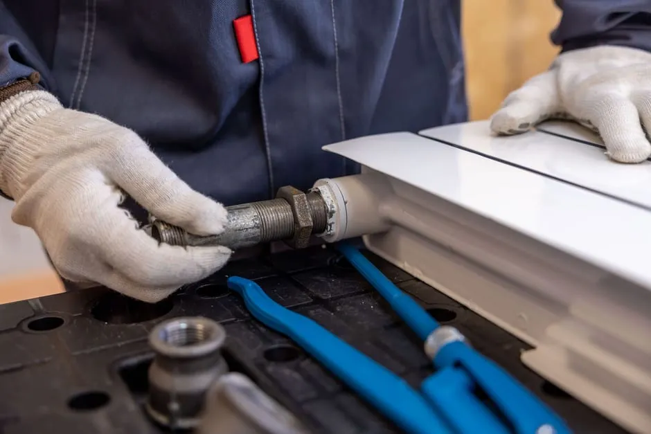 A plumber using hand tools to connect a radiator pipe fitting